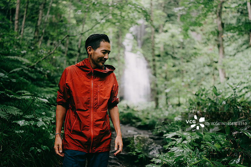在茂密绿色森林中雨中徒步的男人图片素材