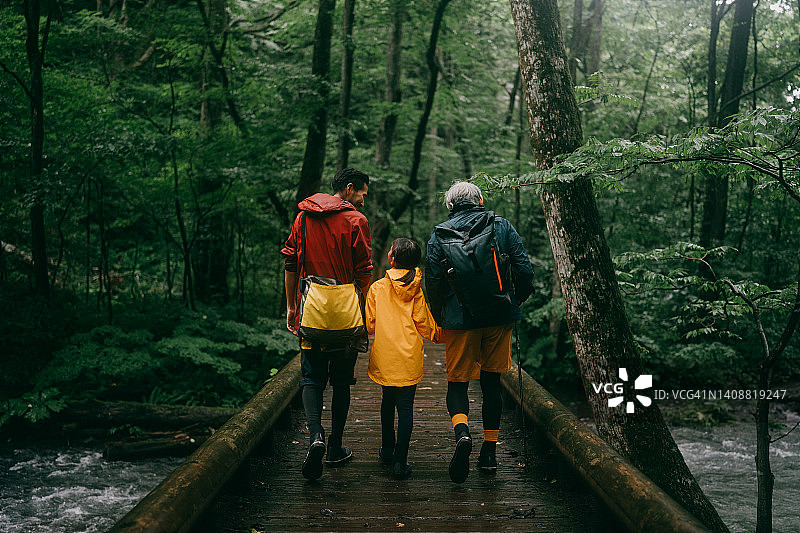三代同堂一家人在雨中森林徒步旅行图片素材
