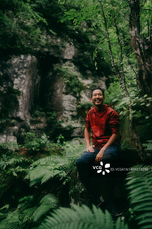 快乐的男人坐在雨中的森林里图片素材