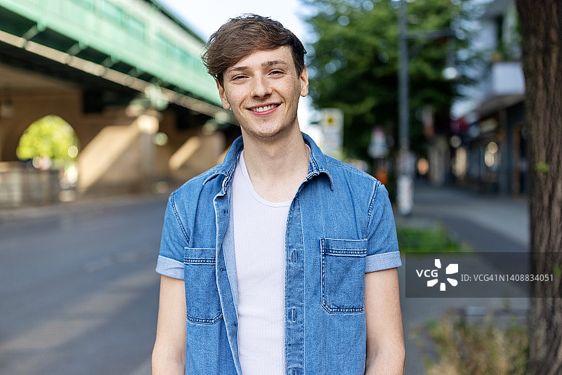 快乐的年轻男子站在城市街道上的肖像图片素材