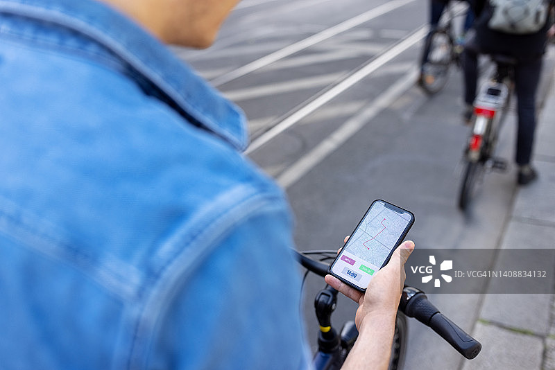 在城市里骑自行车用手机导航的男人图片素材