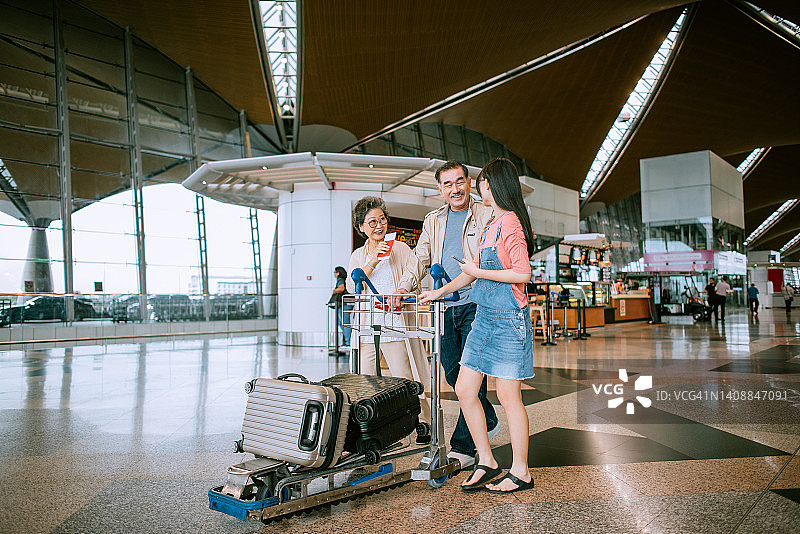 夫妇在机场推着载有孩子的行李车图片素材