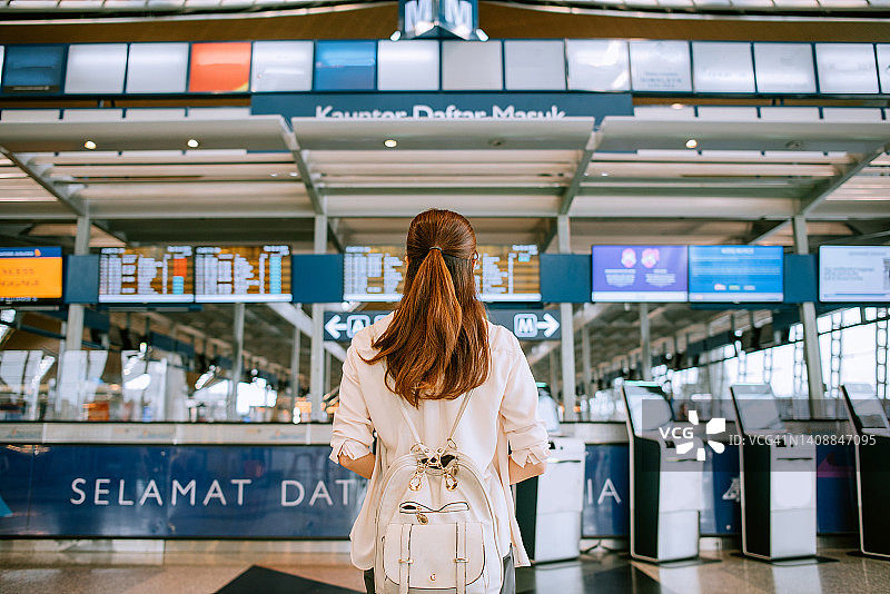 在机场航站楼等候区查看航班信息牌的旅客图片素材