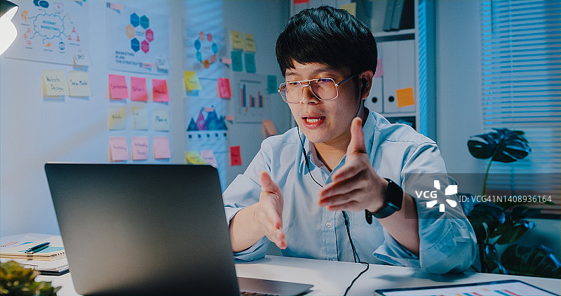 戴着耳机，使用笔记本电脑和平板电脑的年轻商人正在观看在线会议演示营销报告数据图片素材