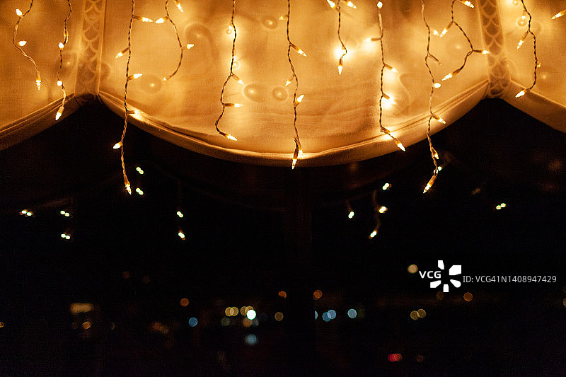 照亮白色扇形边缘帐篷的串灯，远处有抽象灯光图片素材