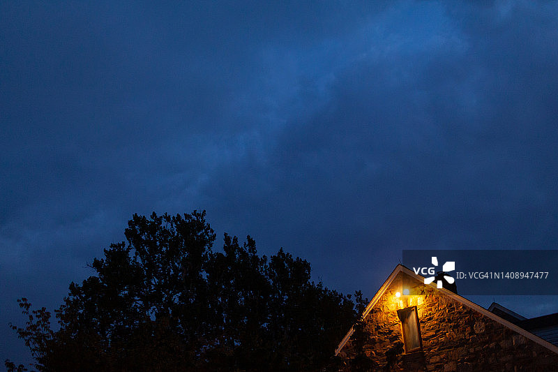 黄昏时分，乡村石 building 旁树顶的仰视角度图片素材