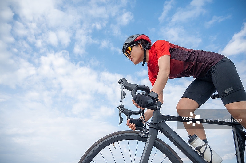 亚洲女性骑自行车，以天空为背景图片素材