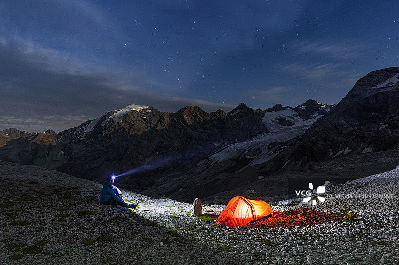 男人在帐篷探险时使用手电筒，地点：斯泰尔维奥山口，松德里奥，伦巴第图片素材