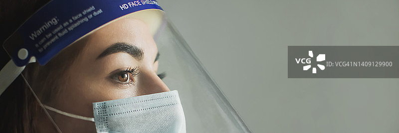 身穿白大褂和防护口罩的年轻医生 портрет，灰色背景。专业制服的医学专家。面罩。防护装备中的漂亮黑发女孩。自信的护士图片素材