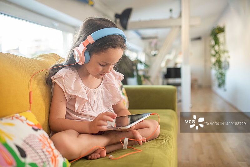 小女孩在平板电脑上玩电子游戏图片素材