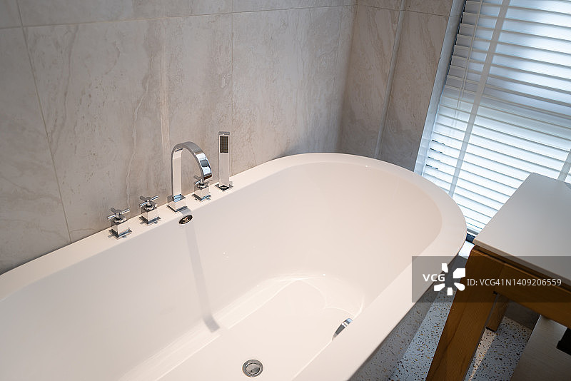 浴室窗边的陶瓷浴缸与水龙头图片素材