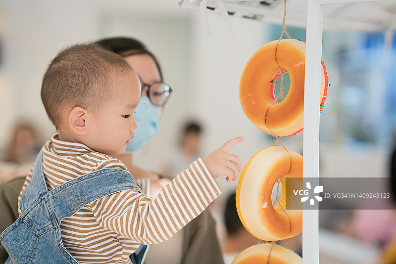 亚洲女性戴着口罩和2岁的儿子一起购物图片素材