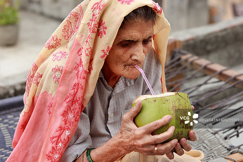 印度老妇人喝椰子水图片素材