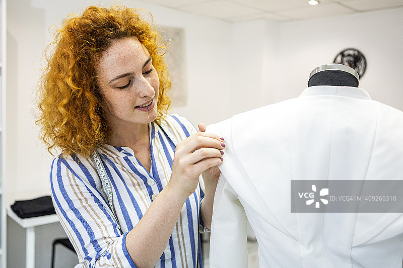 女裁缝测量人体模型手臂尺寸并用针固定图片素材