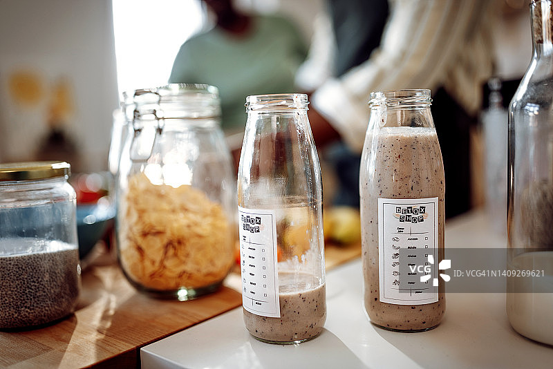 厨房柜台上带有标签的玻璃瓶装冰沙图片素材