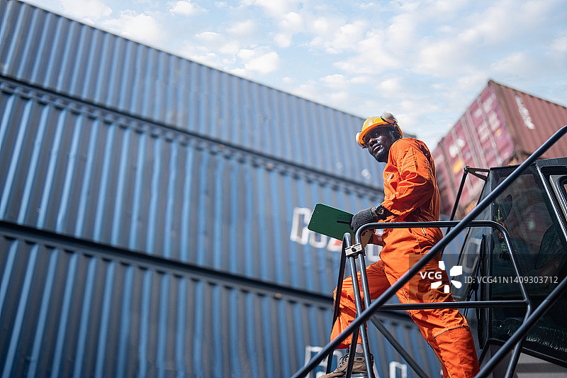 码头调度员身穿防护服，在货运场使用对讲机与集装箱堆垛终端进行通讯。图片素材
