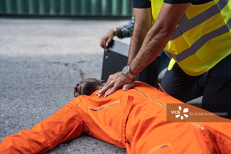 码头商业区一名受伤的码头工人接受同事的心肺复苏术图片素材