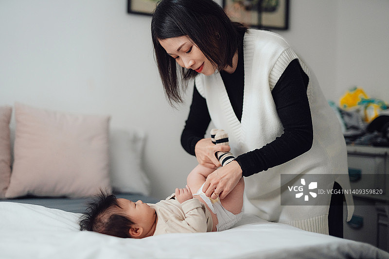母亲为女儿换尿布图片素材