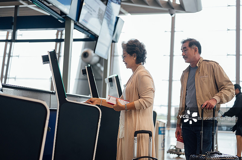 年长的亚洲夫妇在机场使用自助值机图片素材