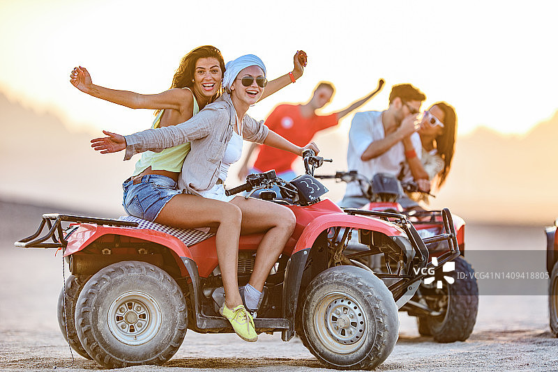年轻快乐的人们在沙漠中驾驶四轮摩托车图片素材