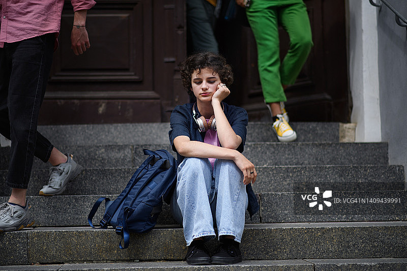 不开心女孩独自坐户外楼梯。图片素材