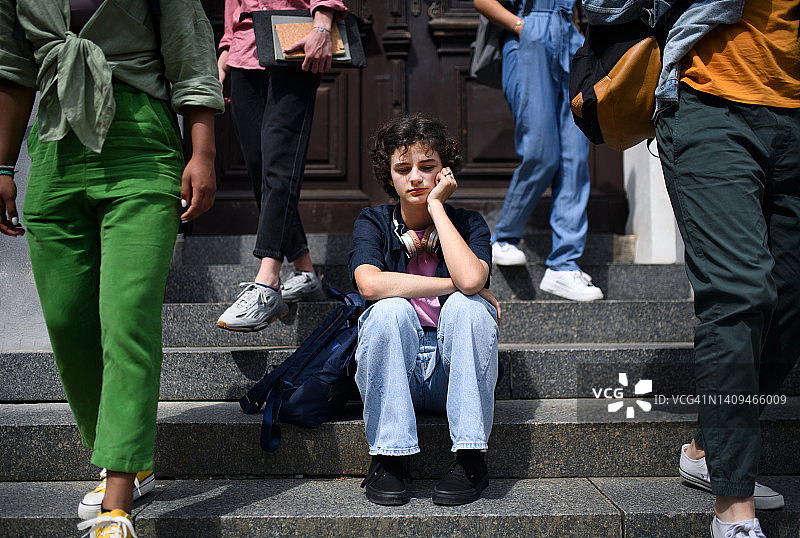 不开心女孩独自坐户外楼梯。图片素材