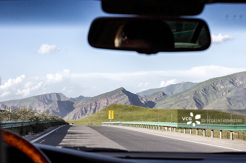 男人在中国西部山区空旷的道路上行驶图片素材