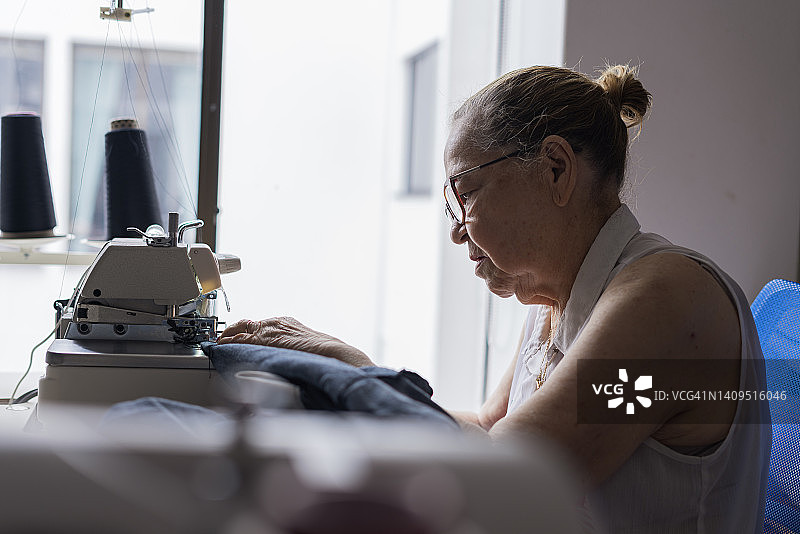 老年妇女在家用缝纫机缝纫，作为爱好图片素材