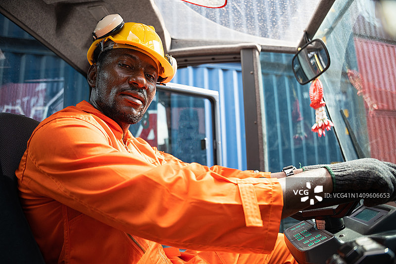 非洲裔男性货物搬运工在货运场操作工业起重机图片素材