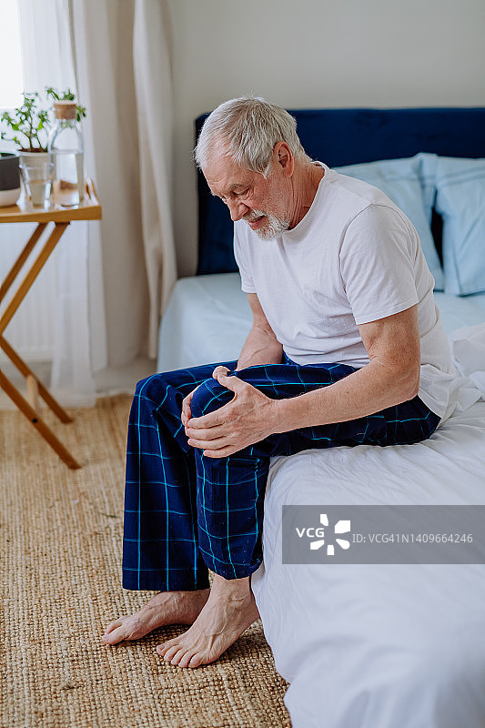 年长的男人坐在床上，膝盖疼痛图片素材