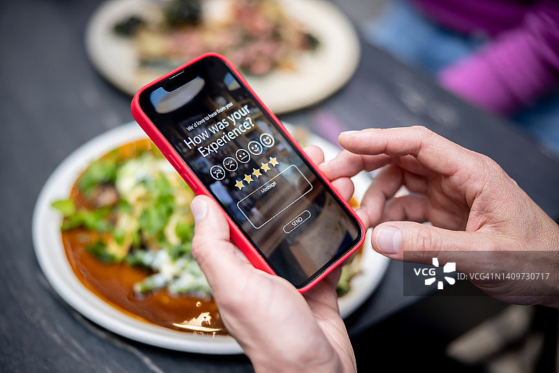 男人使用手机App评价餐厅体验图片素材