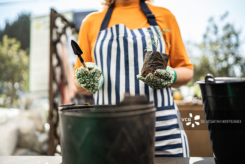 花店店员在园艺中心手持铲子和植物插条图片素材