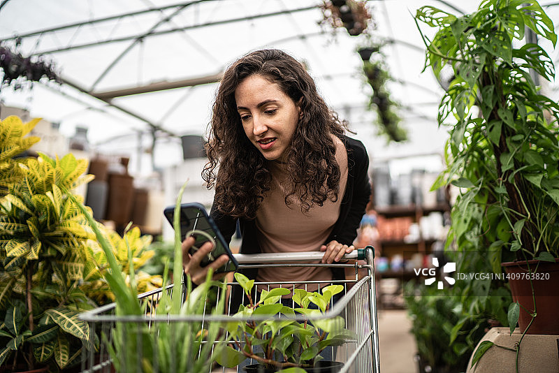 中年妇女在花园中心用手机拍摄植物图片素材