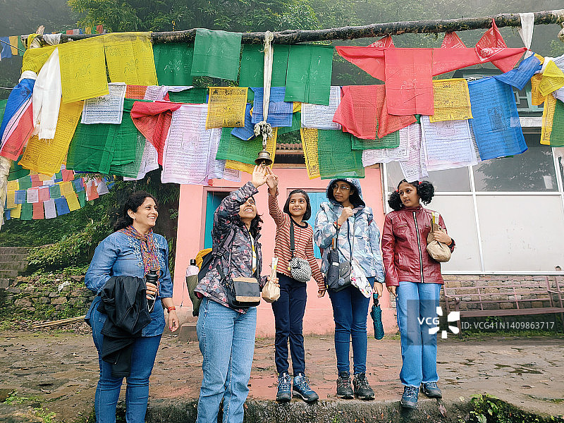 游客们敲响被祈祷旗帜环绕的悬挂金属钟图片素材