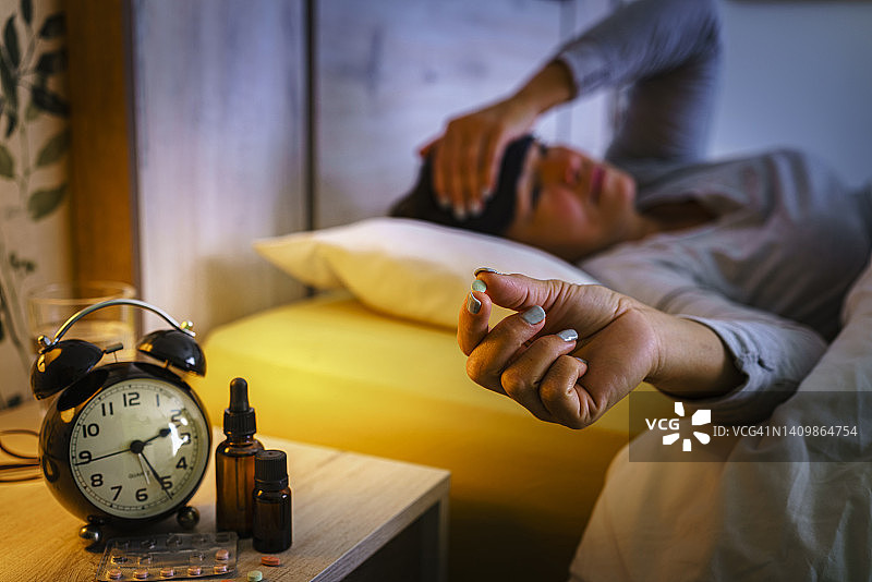 患有失眠和睡眠障碍的忧心忡忡的女人正在服用安眠药图片素材