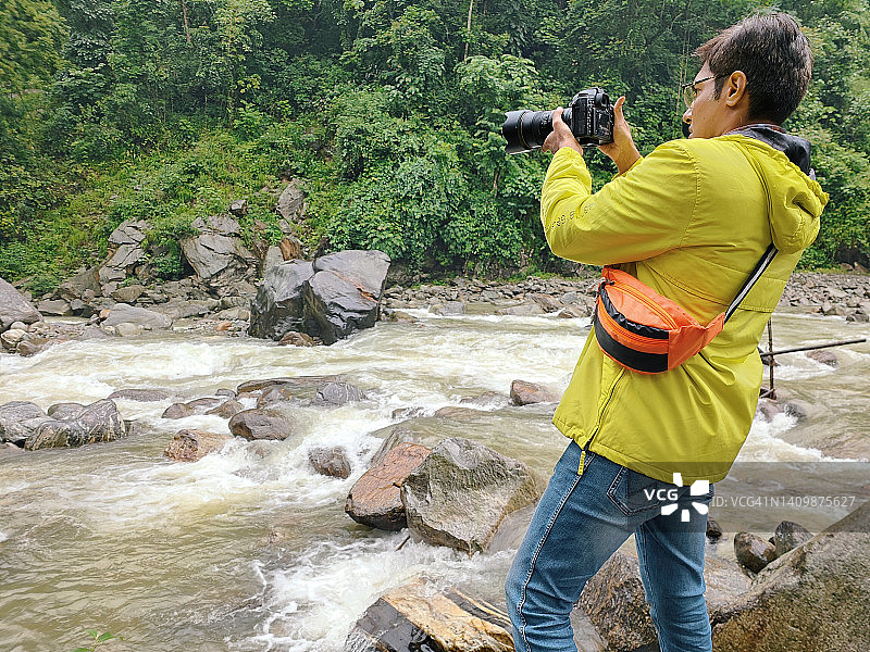 男人在河边用单反相机拍照图片素材