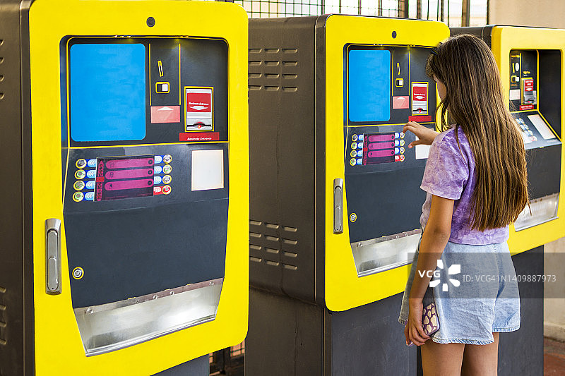 小女孩在户外购买车票或使用自动取款机图片素材