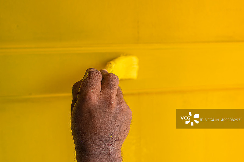 木匠用黄色油漆粉刷旧木屋的窗户图片素材