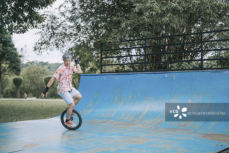 亚洲华人中年男子在滑板公园练习独轮车图片素材