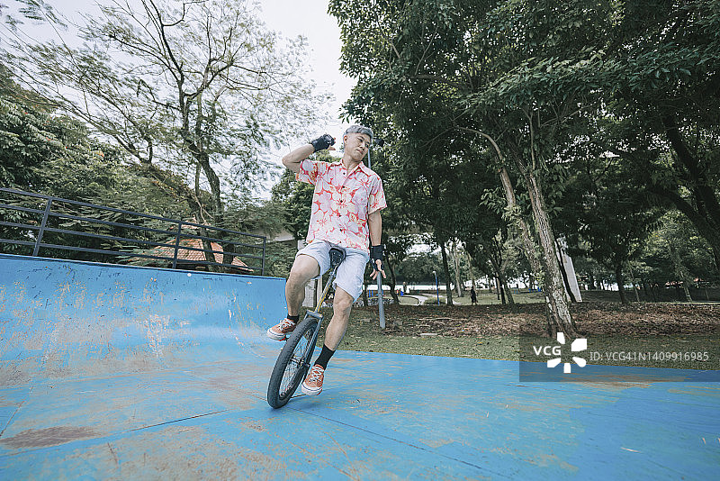 亚洲华人中年男子在滑板公园练习独轮车图片素材