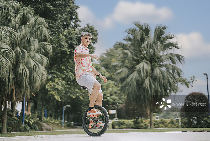 亚洲华裔成熟男子在公园练习独轮车图片素材