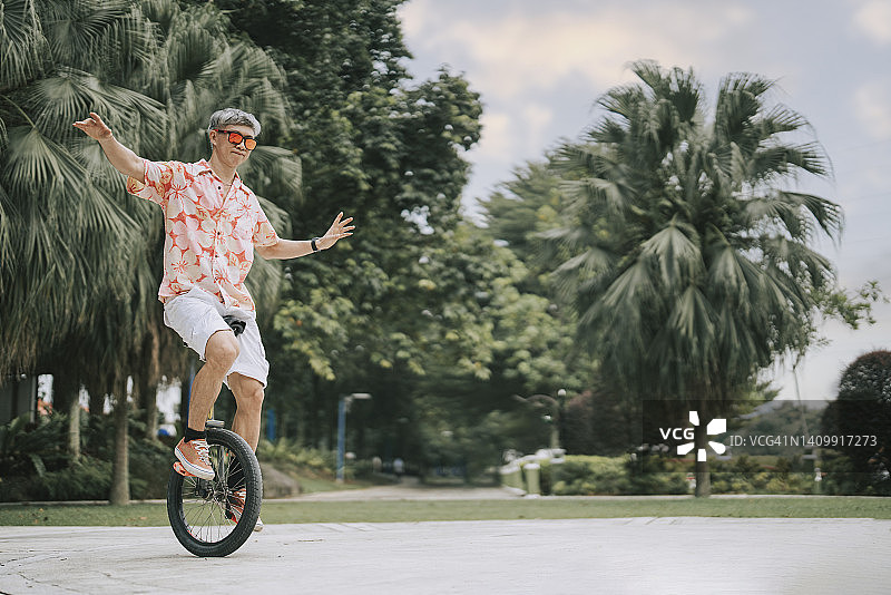亚洲华裔成熟男子在公园练习独轮车图片素材