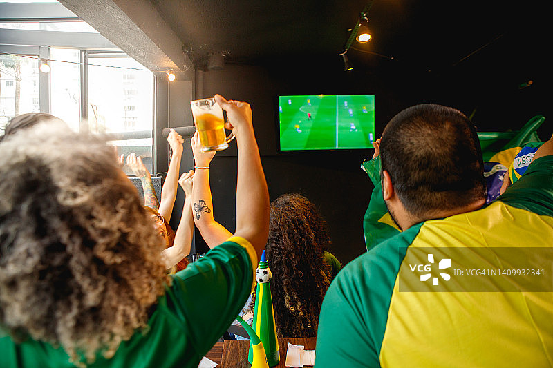 人们在酒吧观看足球比赛并庆祝进球图片素材