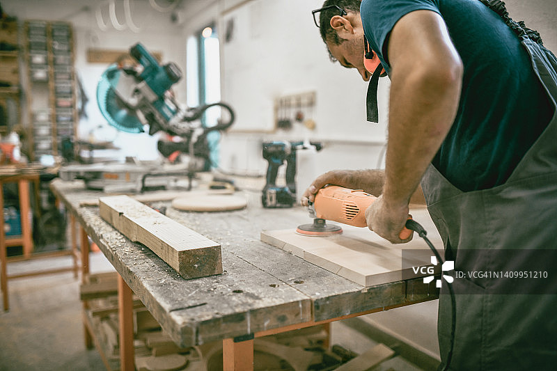 木匠在车间里对木板进行最后抛光的背影图片素材
