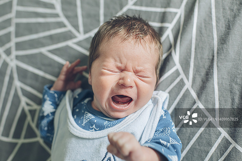哭泣的饥饿新生男婴躺在床上图片素材