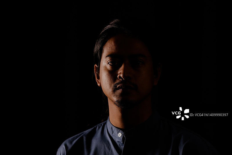 高对比度深色背景下的年轻男人肖像图片素材