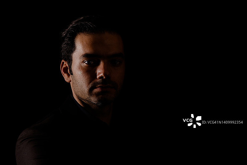 高对比度深色背景下的年轻男人肖像图片素材