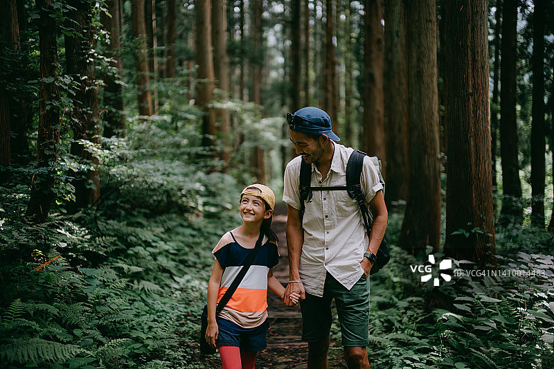 父亲和年幼的女儿在森林里一起徒步旅行图片素材