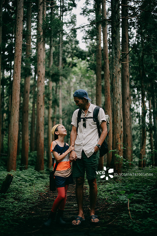 父亲和年幼的女儿在森林里一起徒步旅行图片素材