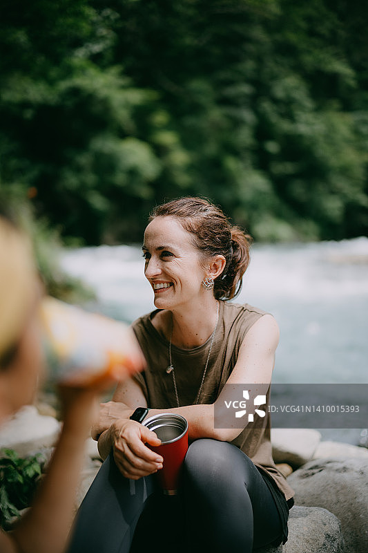 快乐的女人在徒步旅行时在河边休息图片素材